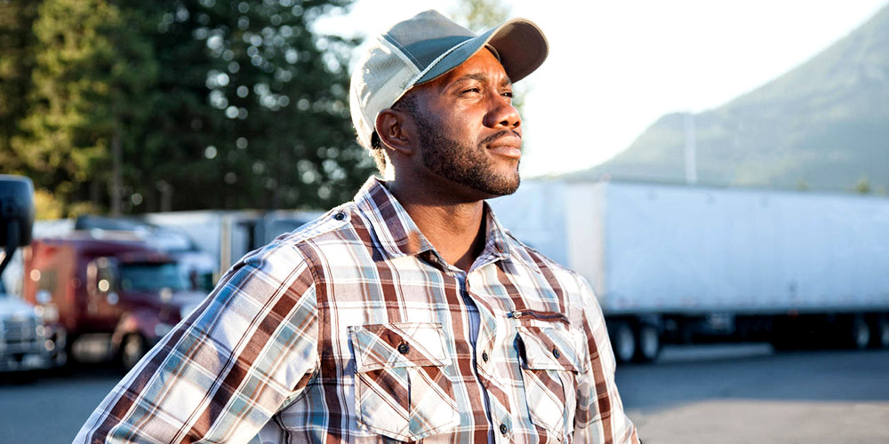 Innovative Learning Solutions_Website Images_Welcome Image African Truck Driver Wearing Cap Standing In Front Of Trucks